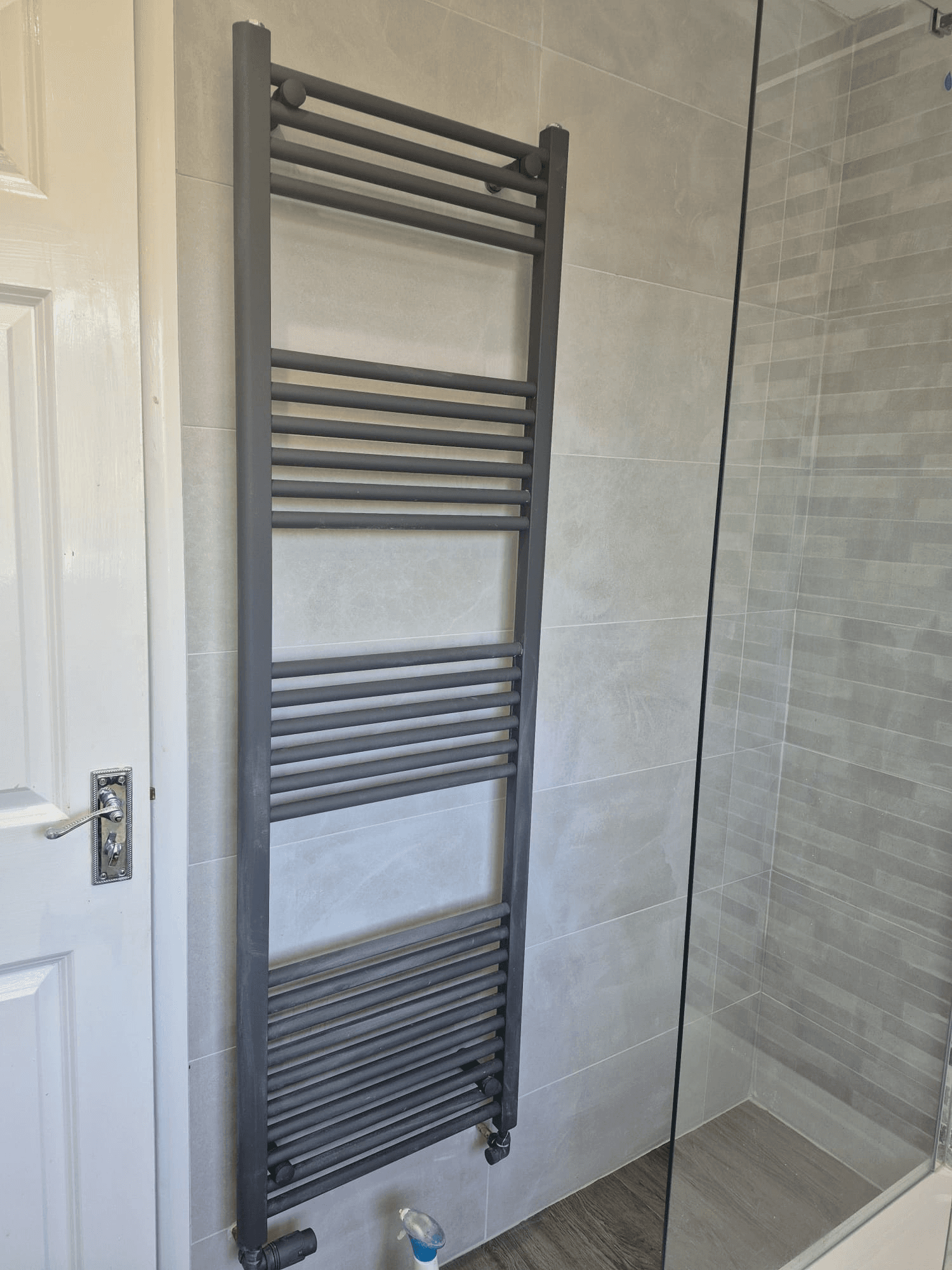 Anthracite heated towel rail beside tiled walk-in shower