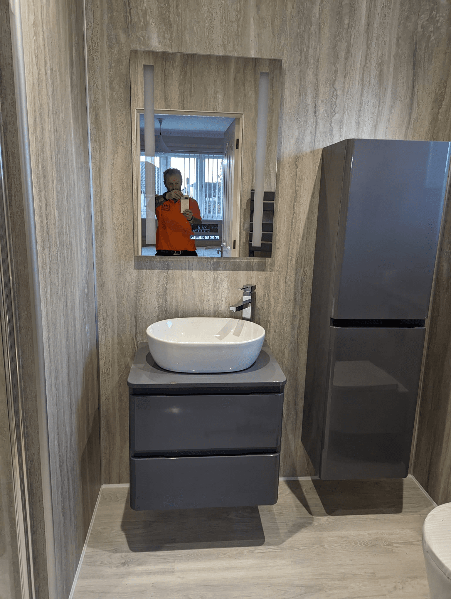Grey floating vanity unit with white vessel basin, rectangular LED mirror and tall grey storage tower