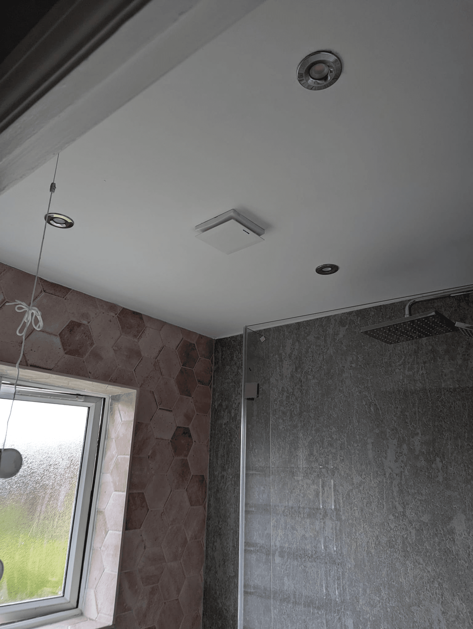 Bathroom ceiling with recessed downlights, pink hexagon feature wall tiles and grey shower area
