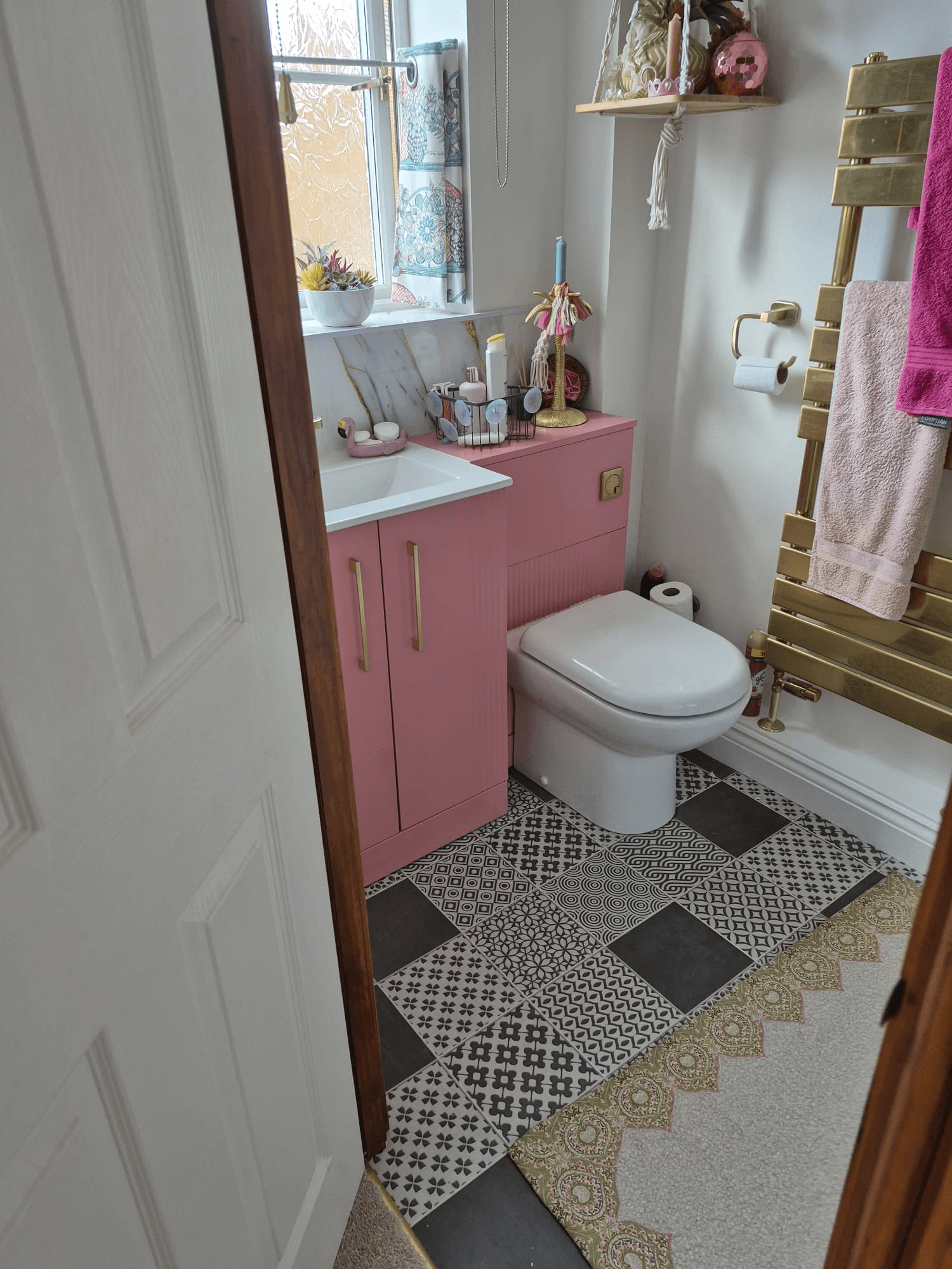 Pink painted vanity unit with gold handles and mixed patterned floor tiles